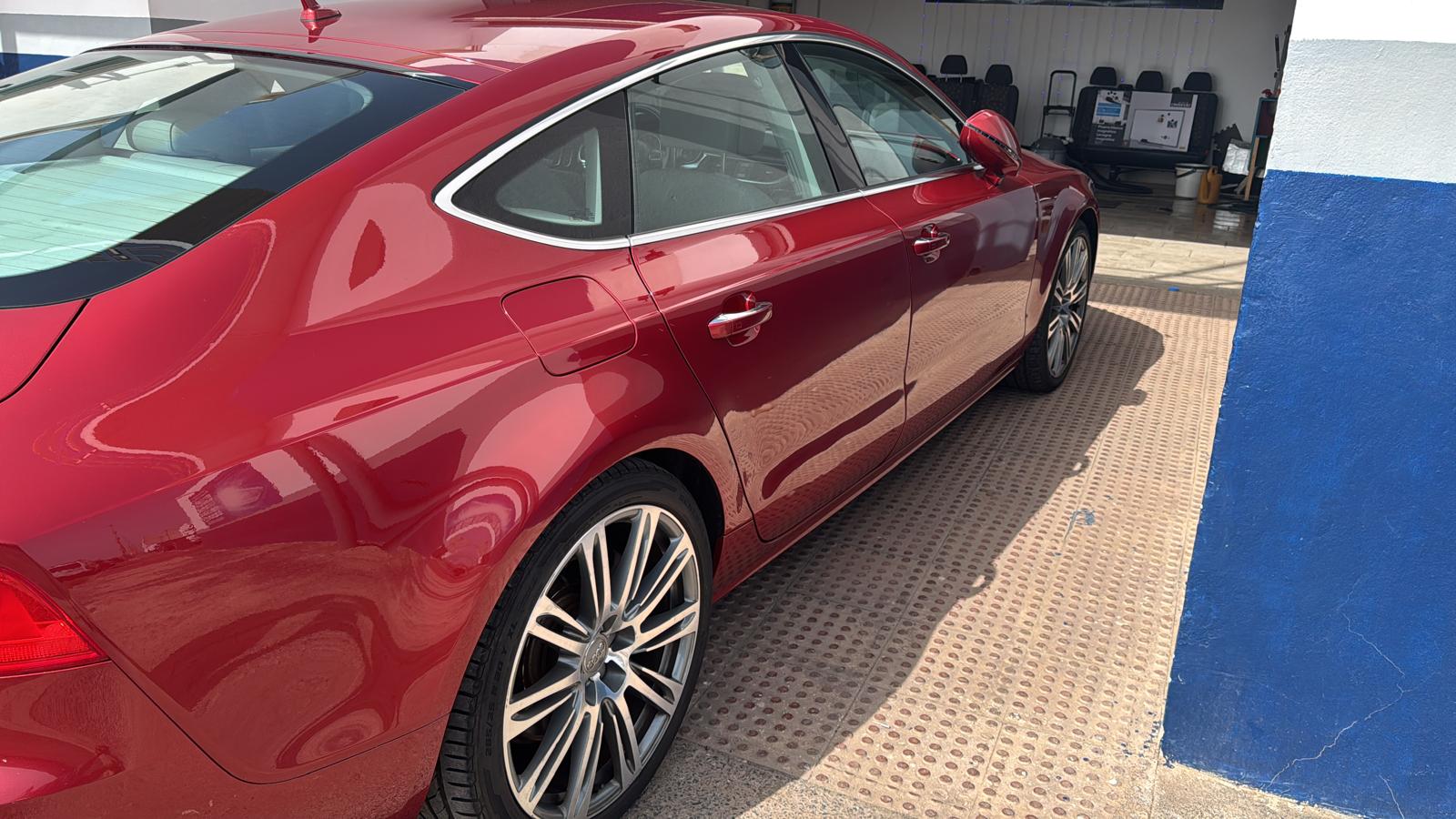 Automóvil rojo de lujo estacionado en un taller, mostrando su diseño aerodinámico y llantas deportivas.