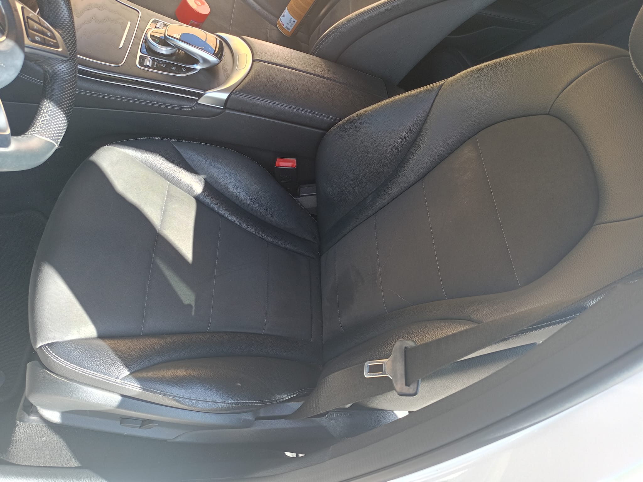 Asiento de automóvil de cuero negro con diseño ergonómico, visible desde el interior del vehículo, mostrando detalles del tapizado y el cinturón de seguridad.