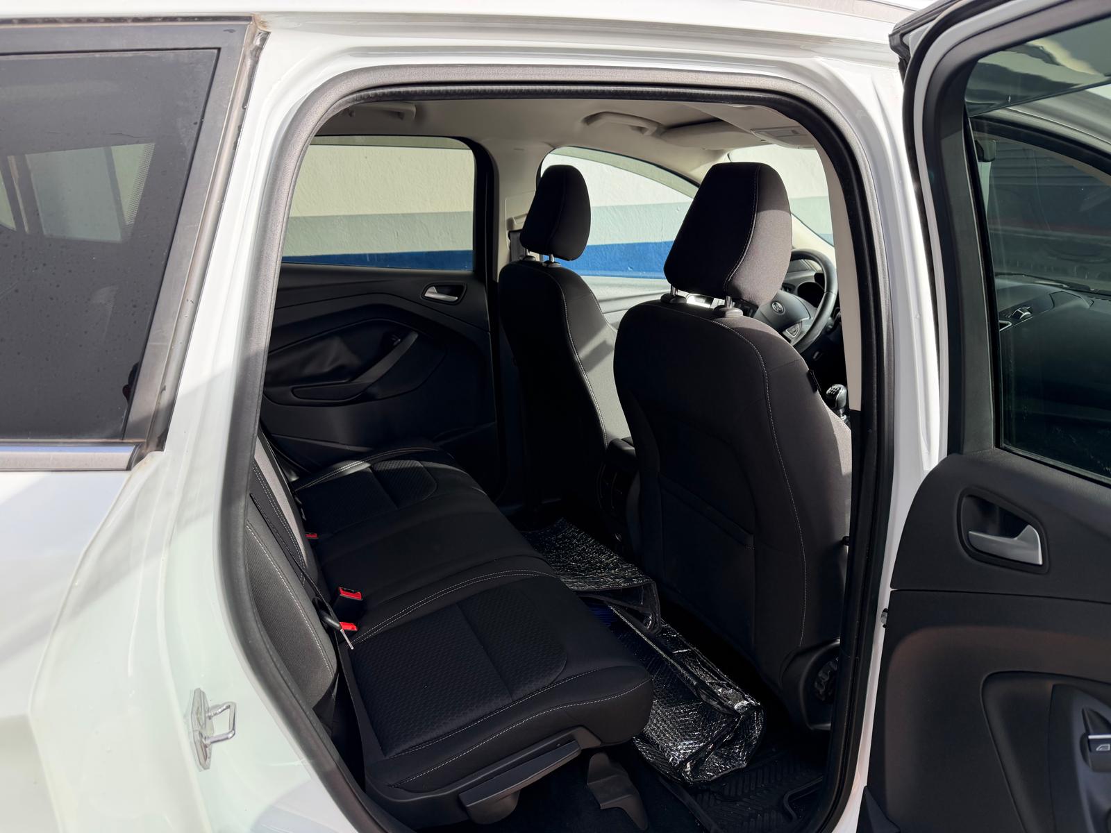 Interior trasero de un automóvil, mostrando asientos de tela negra y espacio para pasajeros. La puerta trasera está abierta, revelando un diseño moderno y cómodo. Ideal para familias o viajes grupales.