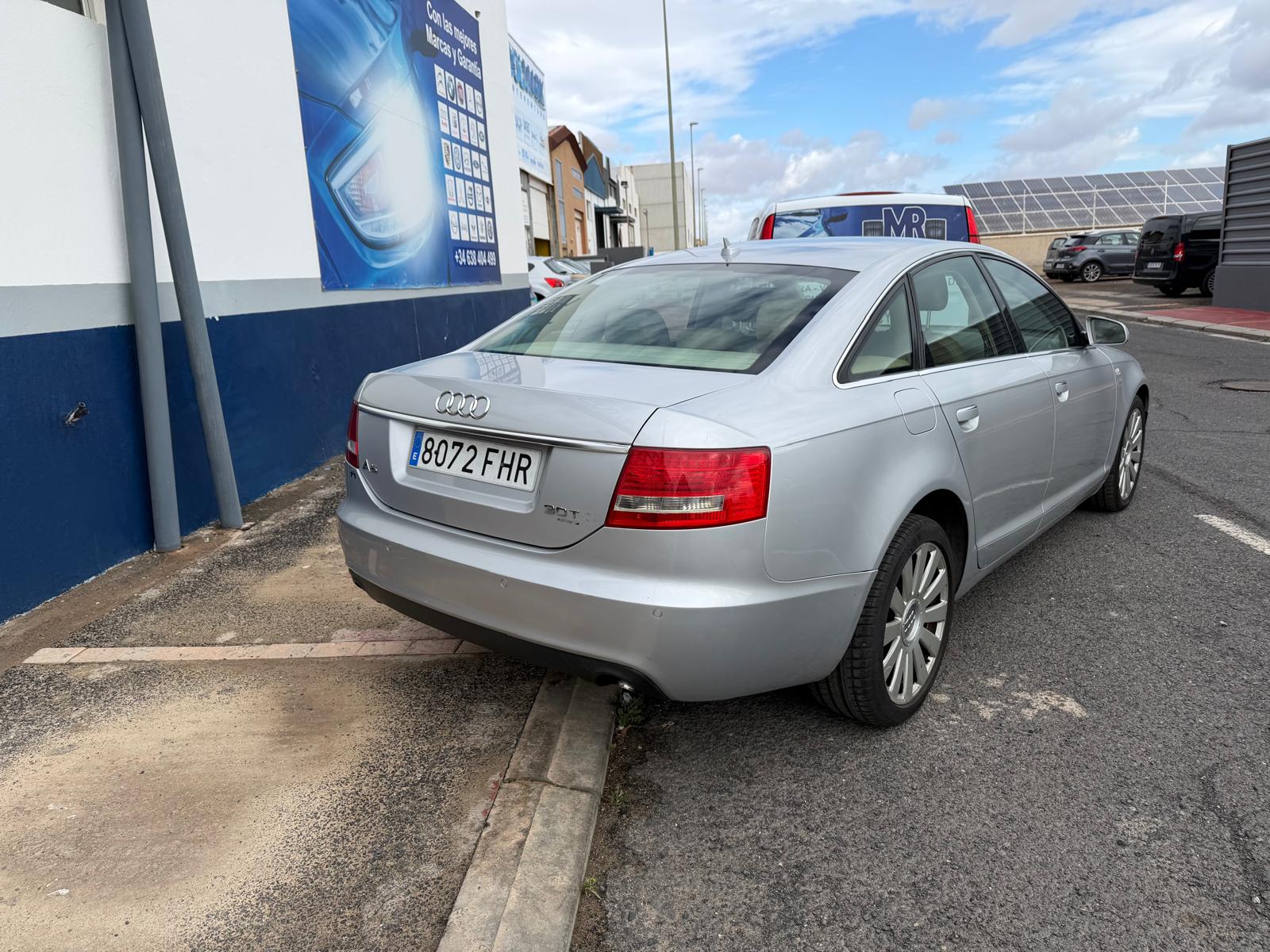 Audi A4 plate 8072 FHR estacionado en la acera, con fondo de una pared azul y un vehículo blanco detrás. Ideal para ilustrar situaciones de aparcamiento en áreas urbanas.
