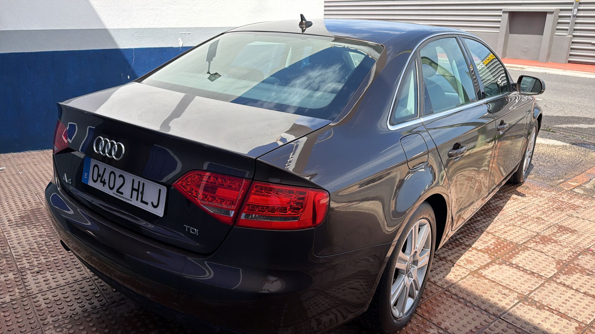Audi A4 TDI negro aparcado, vista trasera con matrícula 0402 HLJ, en un entorno urbano.
