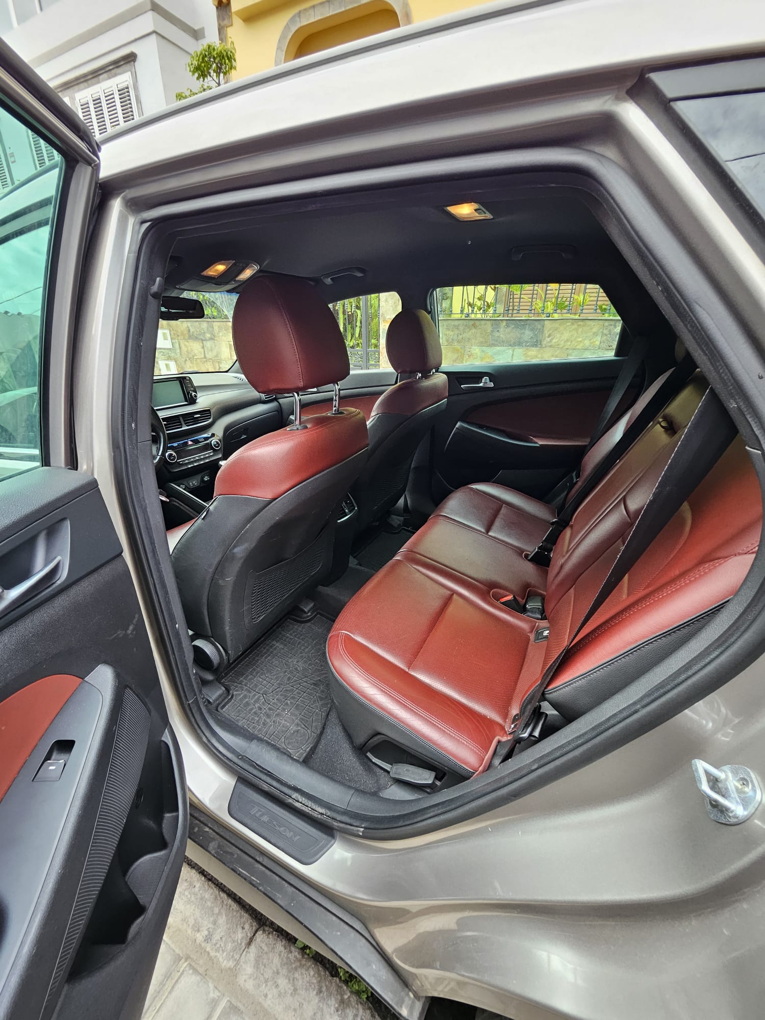 Interior de un automóvil con asientos traseros de cuero rojo y un diseño moderno, mostrando el espacio y la comodidad del vehículo.