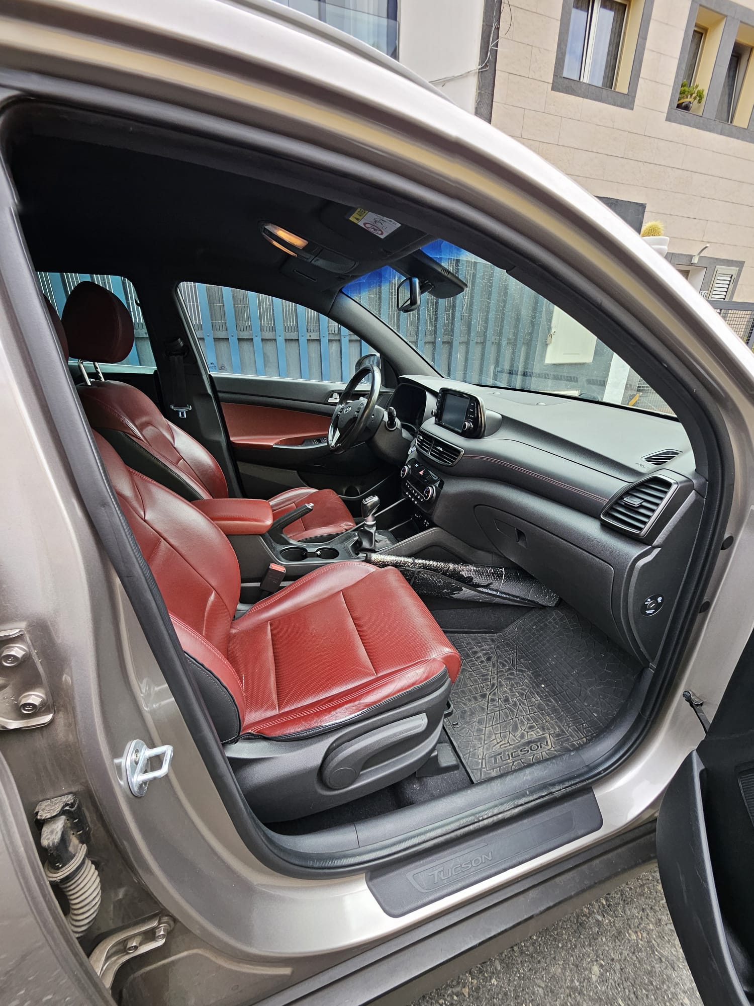 Interior de un automóvil Hyundai Tucson con asientos de cuero rojo, mostrando el tablero, volante y detalles del diseño.