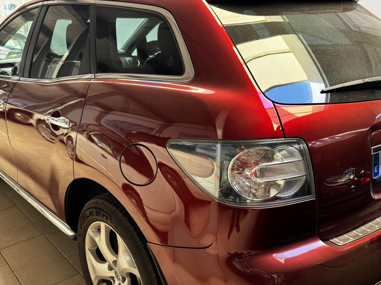 Vista lateral de un automóvil rojo en un garaje, destacando su diseño moderno, llantas y detalles del faro trasero. Ideal para mostrar características de vehículos y opciones de compra.