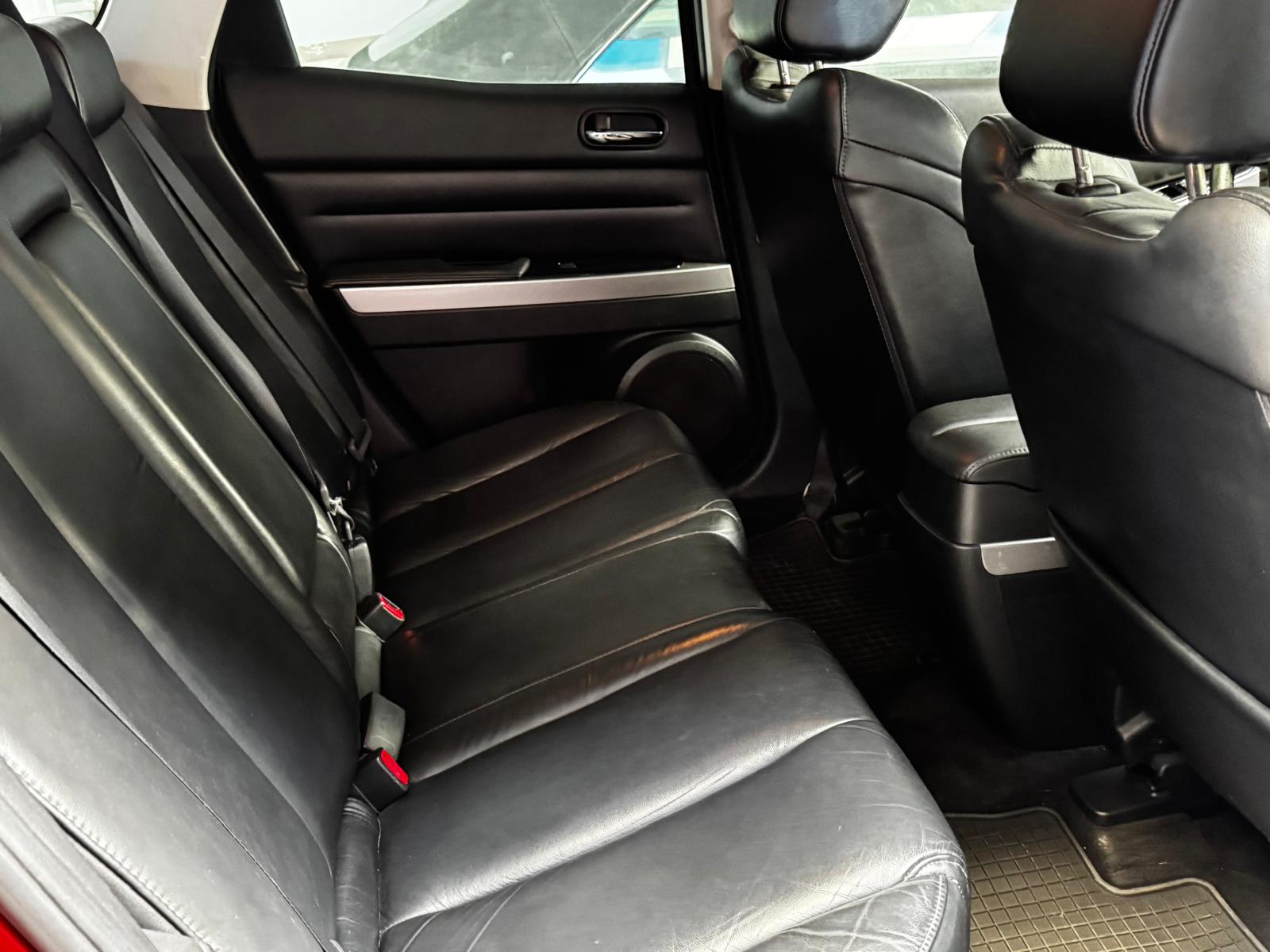 Asiento trasero de un automóvil con tapicería de cuero negro, mostrando espacio y comodidad. Ideal para viajes en familia o con amigos.