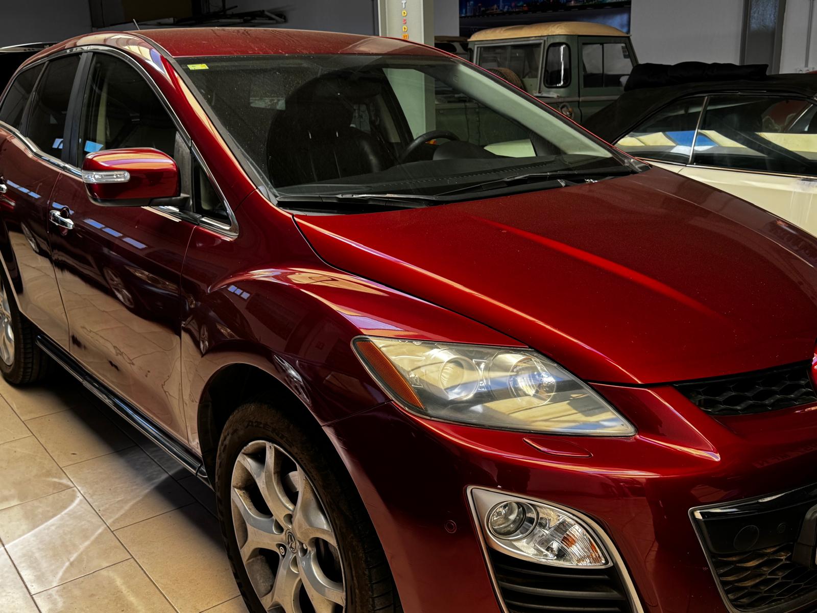 SUV roja en un garaje, destacando su diseño moderno y acabado brillante. Se pueden observar detalles como las llantas y los faros delanteros.