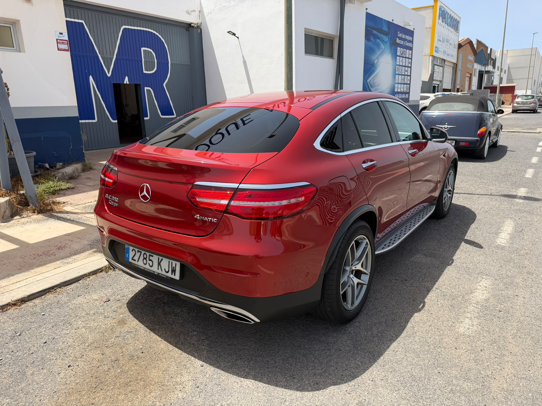 Mercedes-Benz GLC Coupe rojo estacionado en una calle, con un diseño elegante y moderno, mostrando detalles de la parte trasera y lateral, incluyendo llantas deportivas y el emblema 4MATIC.