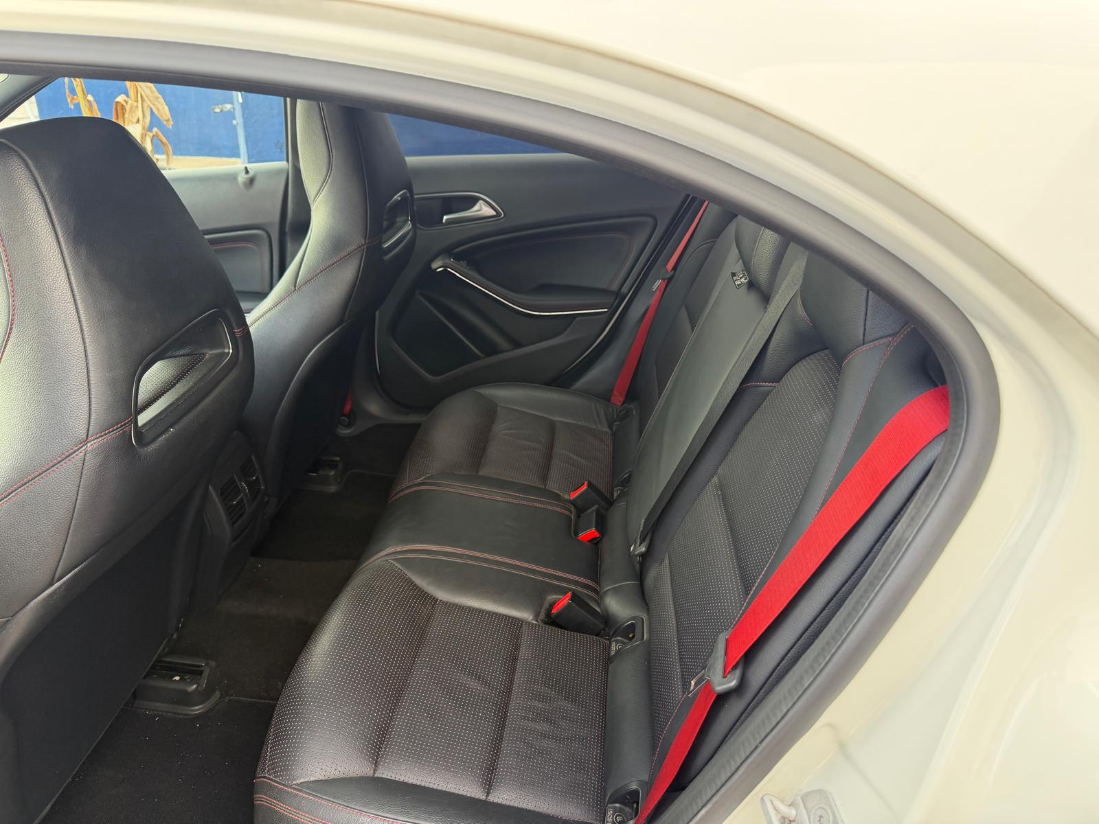 Interior trasero de un automóvil con asientos de cuero negro y detalles en rojo, mostrando un diseño moderno y deportivo.